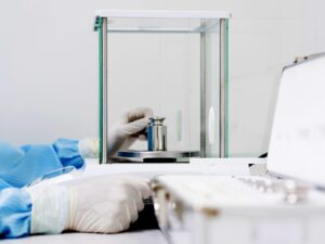 Technician places a calibration weight on an analytical balance