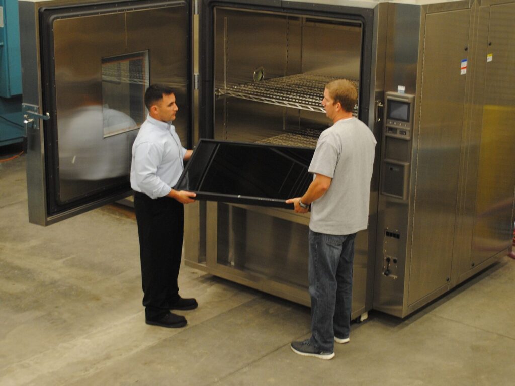 Two engineers load a product into a thermal chamber in our temperature testing lab