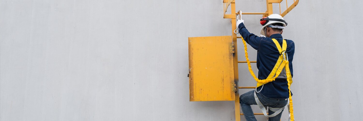 Technician in a fall arrest system climbs an industrial ladder