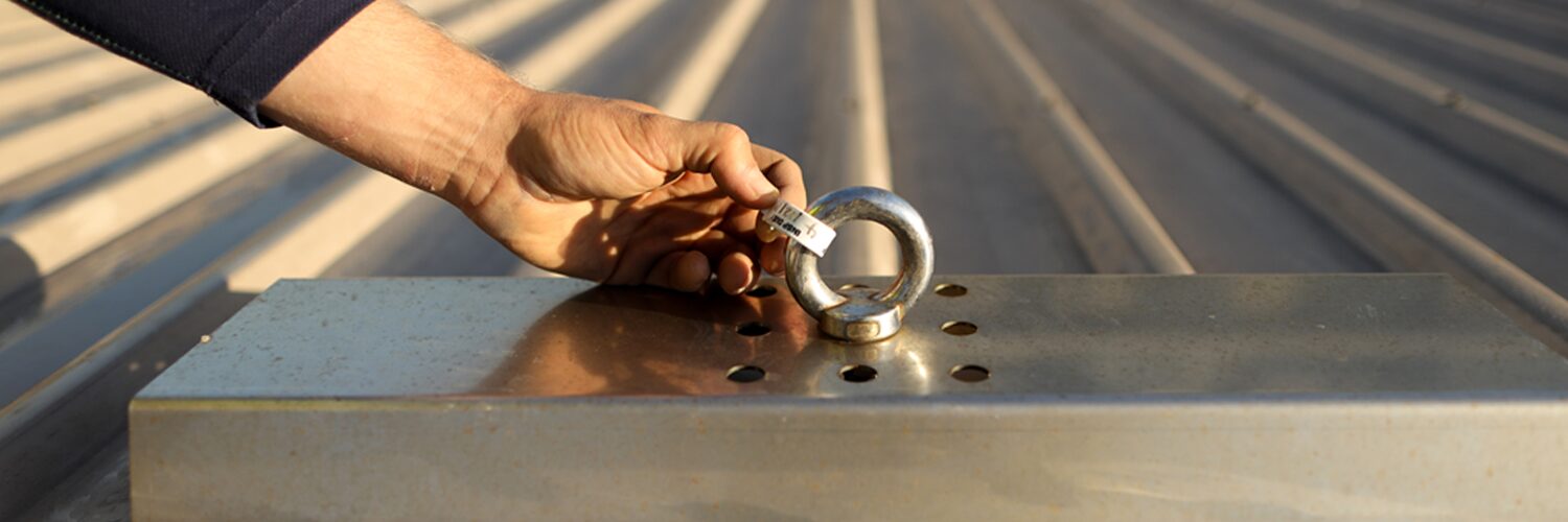 Hand holds a tag on a roof anchor