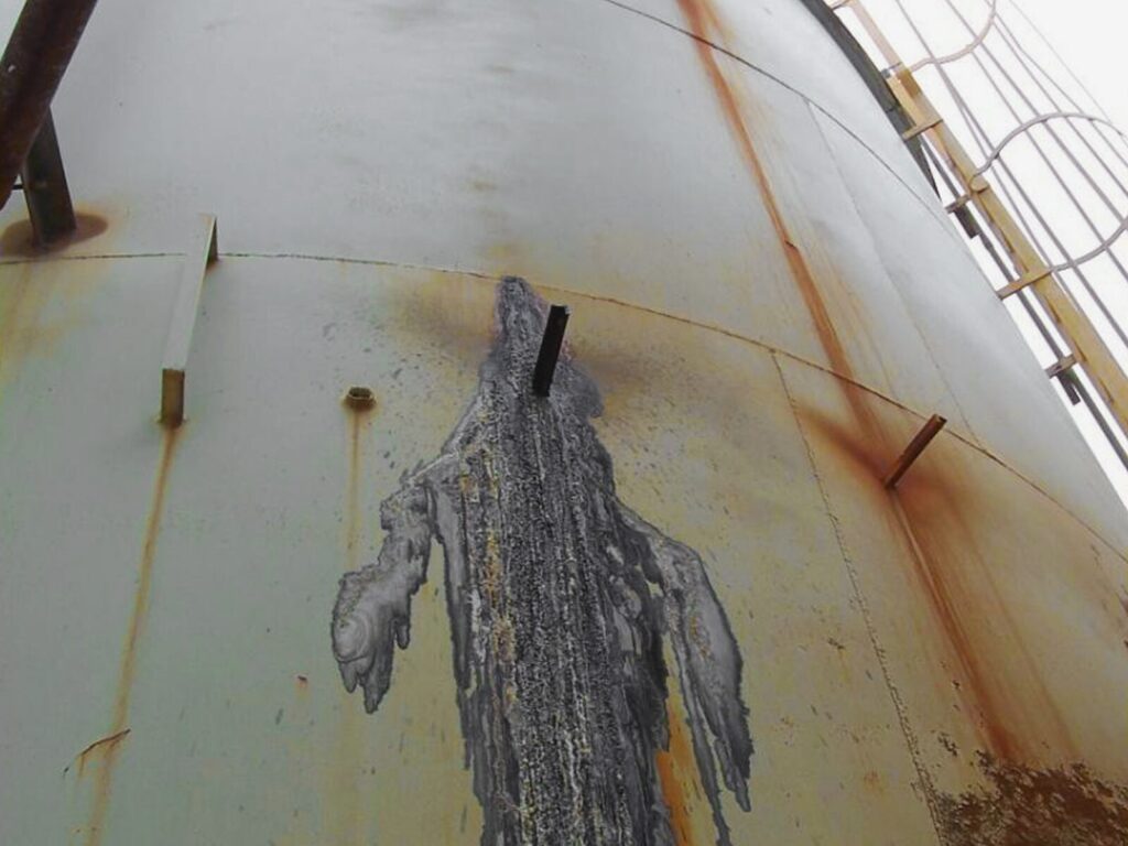 Aboveground industrial tank with a prominent stain from a leak
