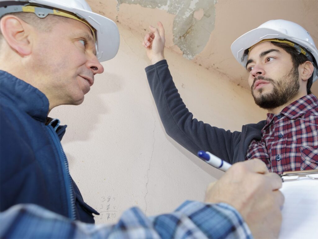 Two engineers discuss a leak in the ceiling