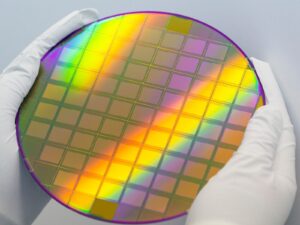 Scientist holds a large silicon wafer for radiation testing