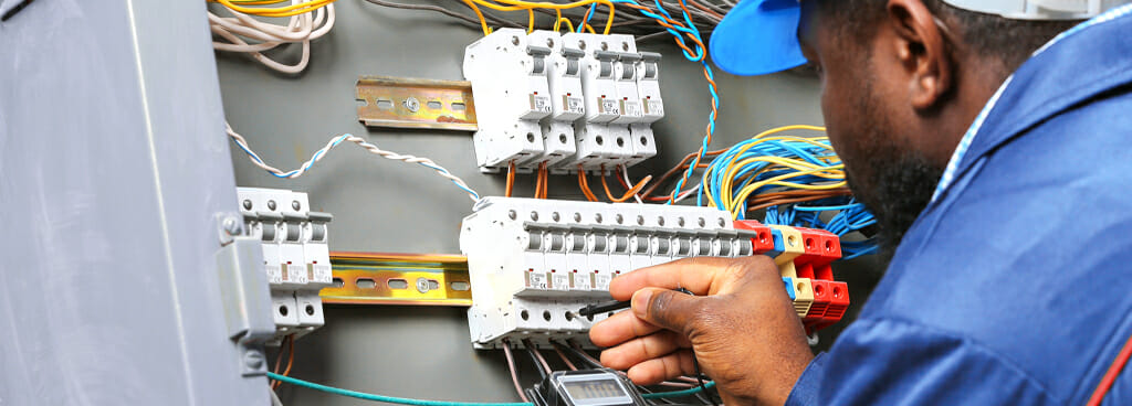 A forensic electrical engineer uses a voltage checker on a distribution board.