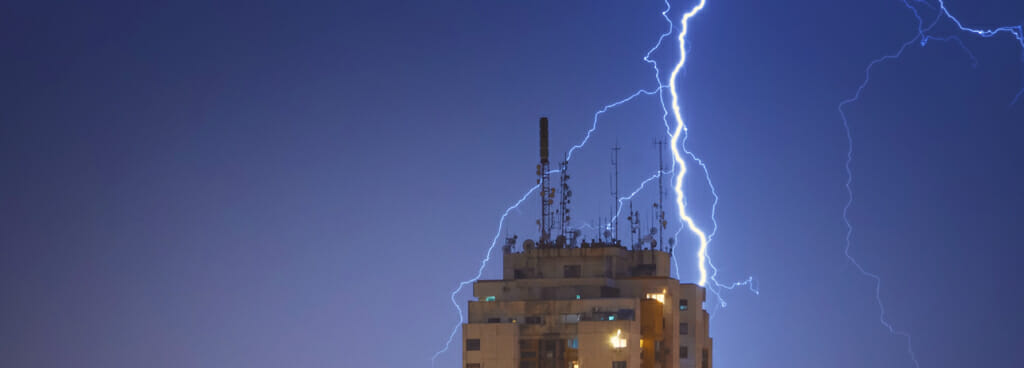A bolt of lightning flashes around a skyscraper with a lightning protection system designed for tall buildings.