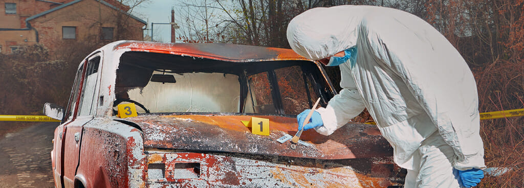 A certified arson investigator samples trace evidence on a burned vehicle.