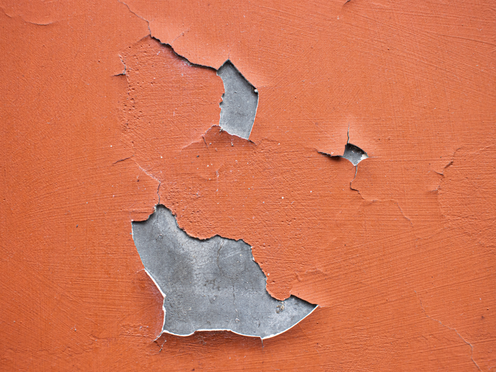 Red coat cracks and delaminates from a concrete wall