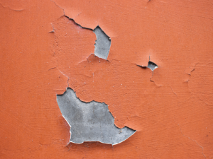 Red coat cracks and delaminates from a concrete wall