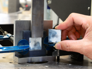 Technician grips one half of a bar after shear failure