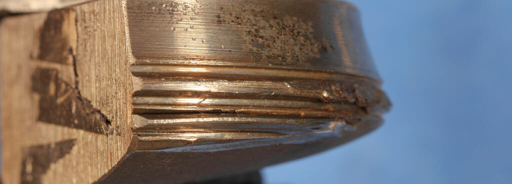 A compressor rod shaft after undergoing accelerated fatigue testing. The specimen is corroded and fractured in half.