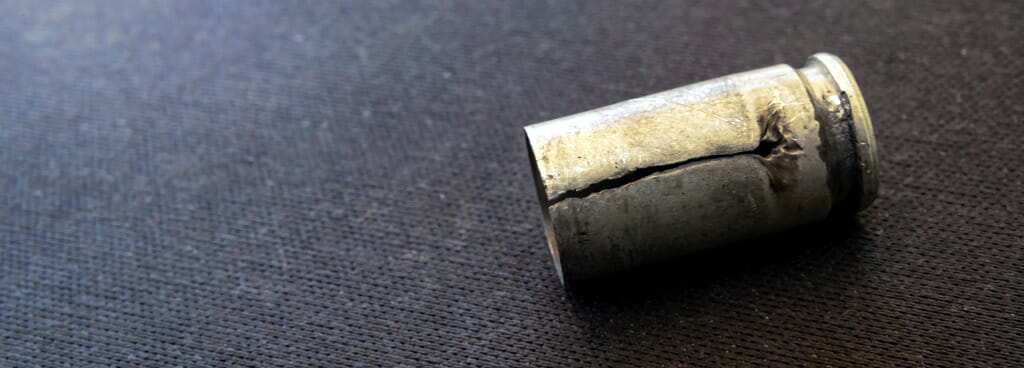 A cracked bullet casing on the floor. Manufacturers may want to try fatigue testing methods to discover why the crack occurred.