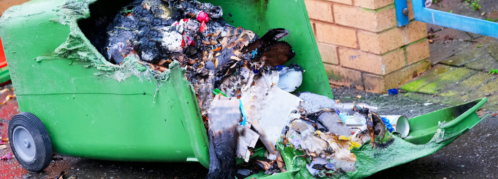 The charred contents of a burned trash bin after arson.