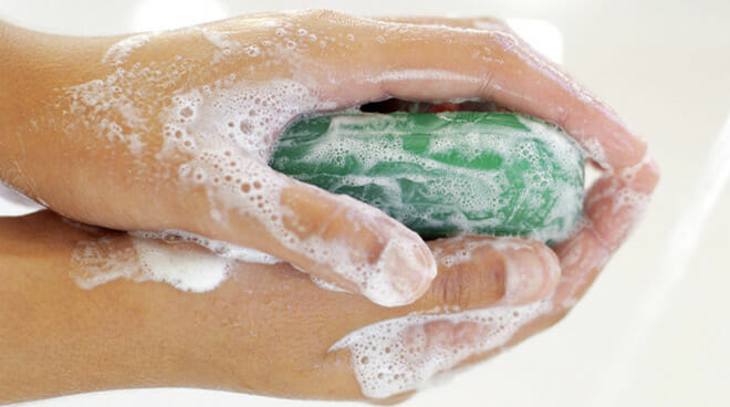 A pair of sudsy hands holds a green bar of soap that may fall under emerging 1,4-dioxane standards in your state.