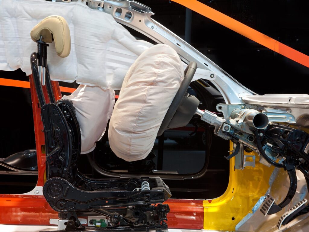 Driver's seat and deployed airbags of a vehicle. Half of the vehicle is exposed for forensic investigation.
