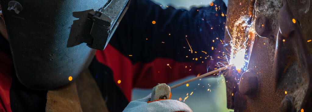 A welder performs 3g MIG welding for a certification test.
