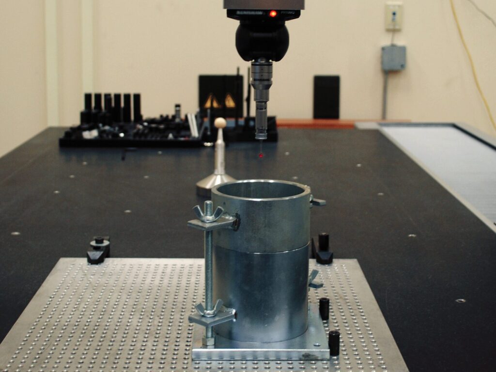 Focus on an upright pipe and CMM probe during a coordinate measurement scan