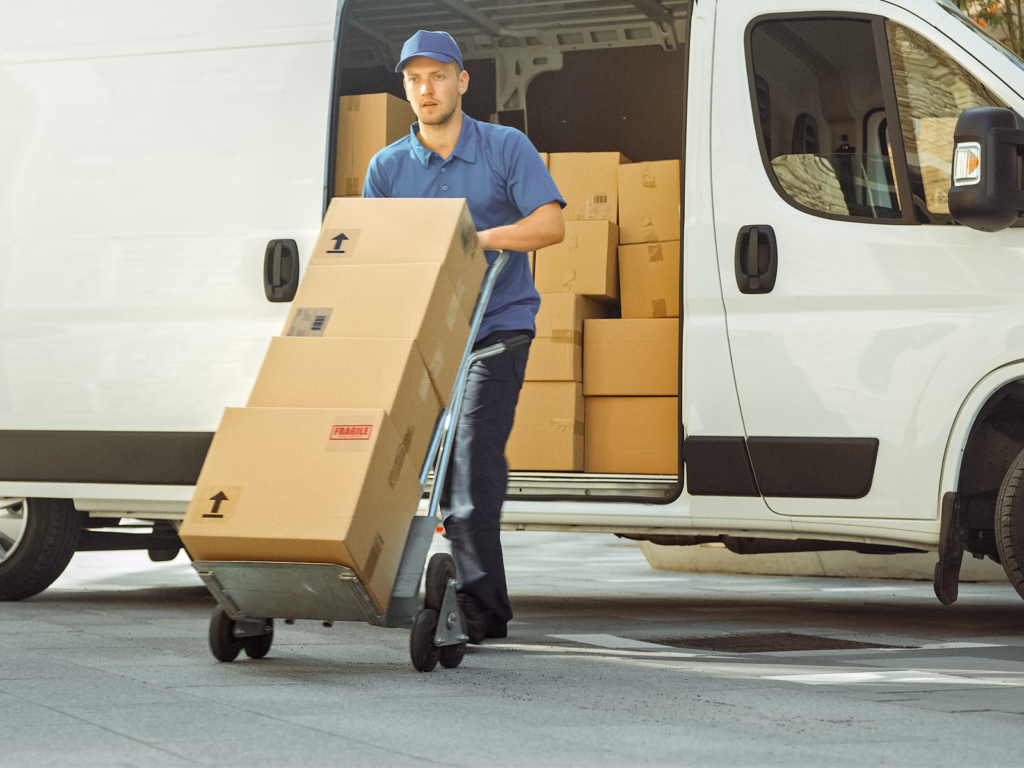 Delivery man pushes a cart of cardboard packages
