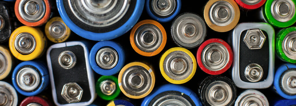 Overhead view of a multicolor collection of batteries. Some are cylindrical, others prismatic.