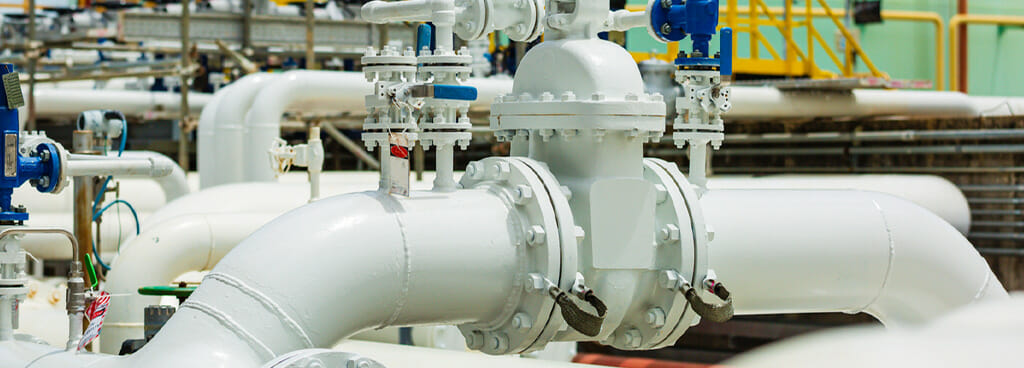 A mass flow meter attached to a gas piping system. The industrial pipes are large and white.