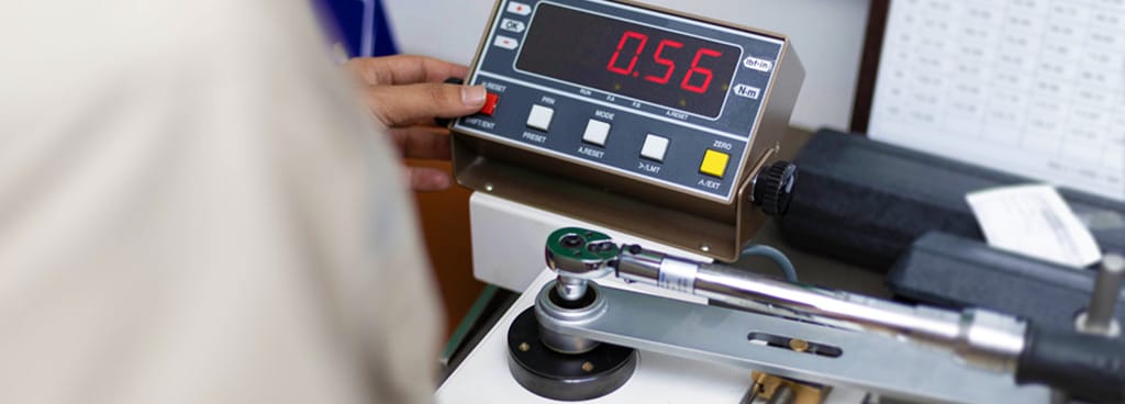 A technician performs torque wrench repair and calibration on a digital machine set to 0.56 ppm.