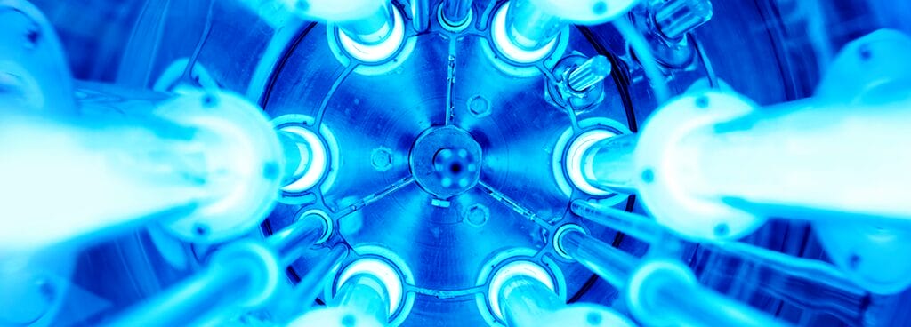 The interior of an ultraviolet lamp. Multiple coils emitting bluish light stretch toward the camera in a cylindrical shape.