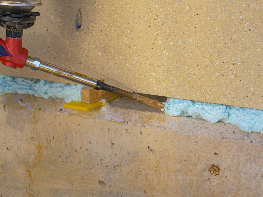 A contractor applies polyurethane foam between cinder blocks of a building