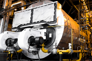 A large grey industrial pressure vessel operates inside a facility.