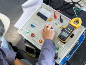 Electrical engineer turns a dial on a high potential (HiPot) testing machine.