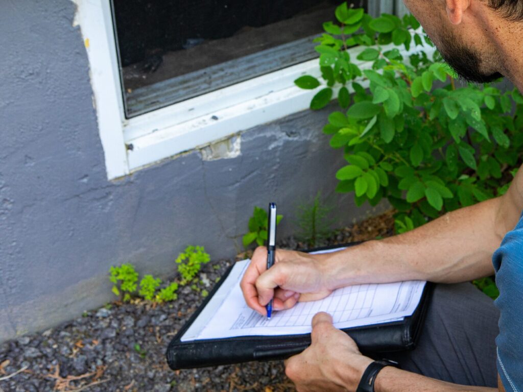 Inspector takes notes on a leak where a building envelope meets a window pane