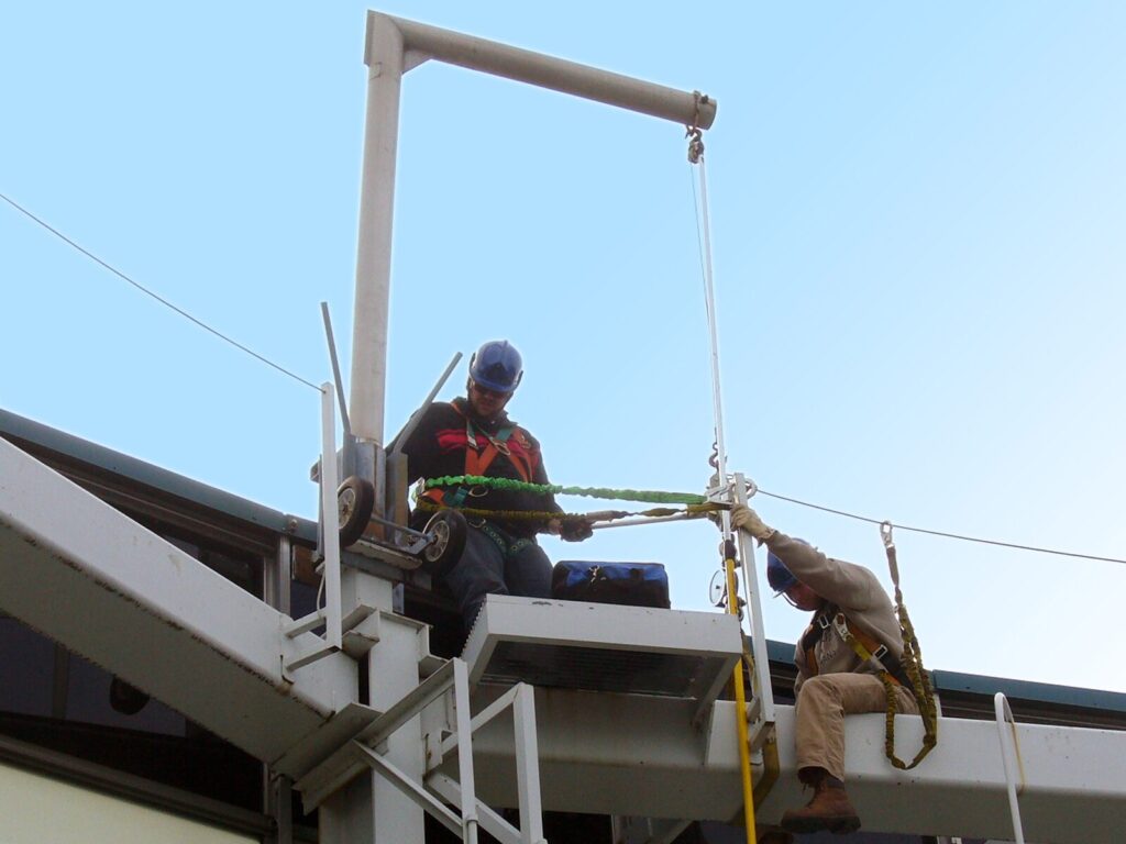 Two rope access technicians inspect a fall protection davit system