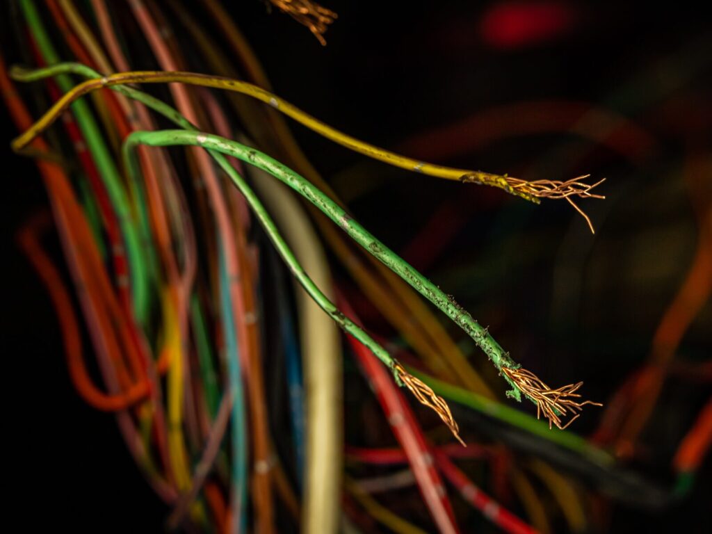 Exposed and frayed electrical wires with black spotting from burns