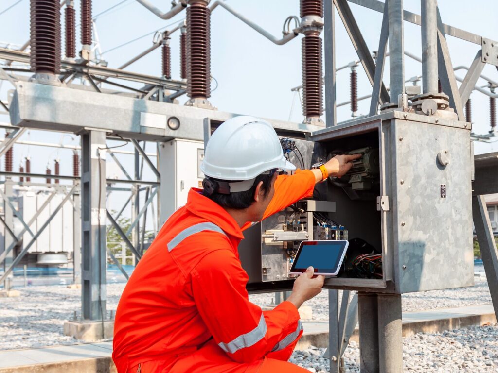 Technician crouches in front of a control panel for electrical forensics