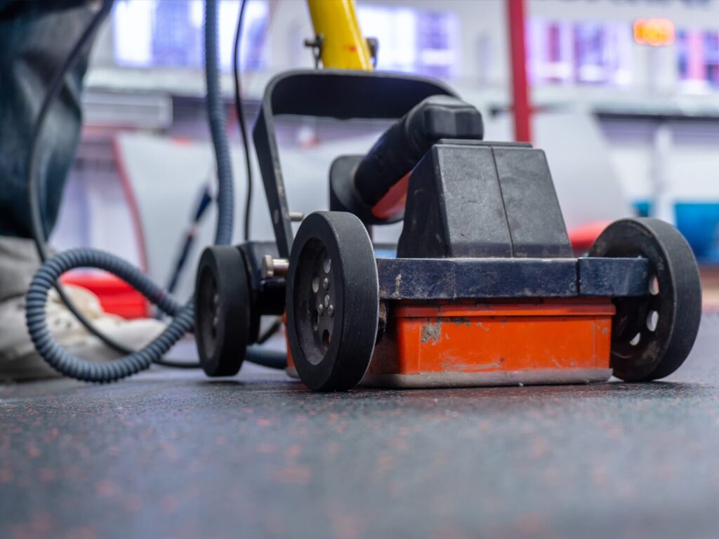 A technician pushes a ground penetrating radar machine. Picture taken low to the ground.