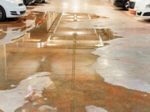 Parking garage with a massive water leak pooling around a row of cars