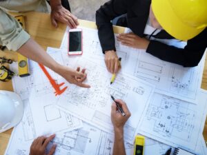 Three structural engineers point to the blueprints for a building