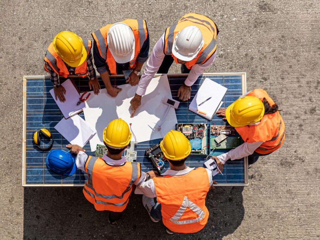 A team of engineers in hard hats study the blueprints for a building
