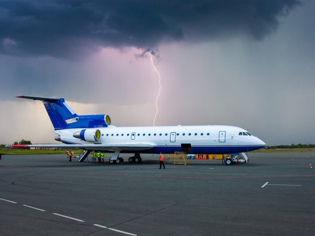 A grounded airplane on tarmac during a lightning storm