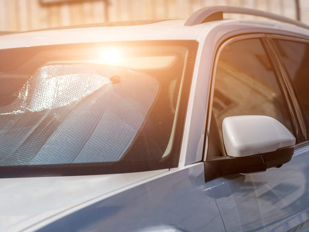 Hot sun reflects off the windshield of a car