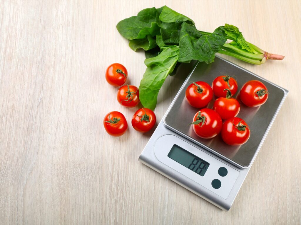 Digital kitchen scale with tomatoes and spinach leaves