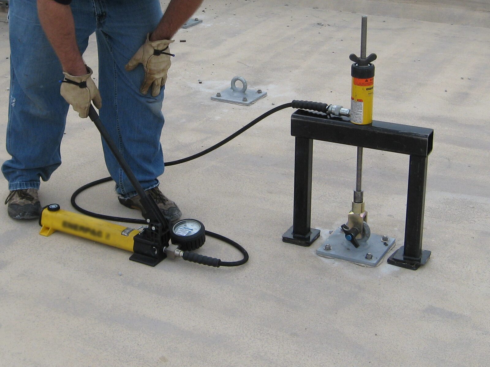 Roof technician performs a pull test on a roof anchor