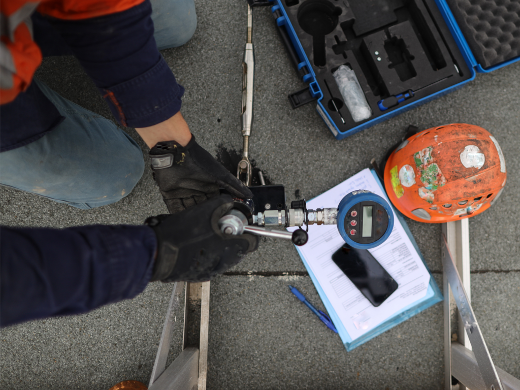Roof inspector performs a pull test on a roof anchor
