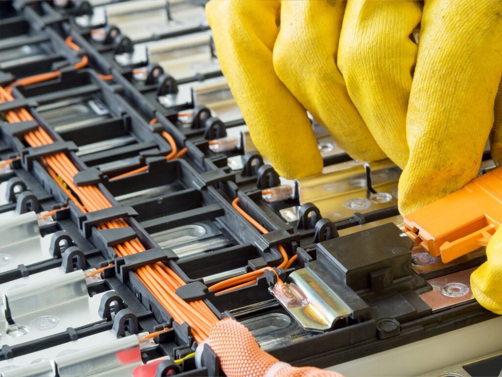 Technician wearing yellow gloves adjusts a battery pack