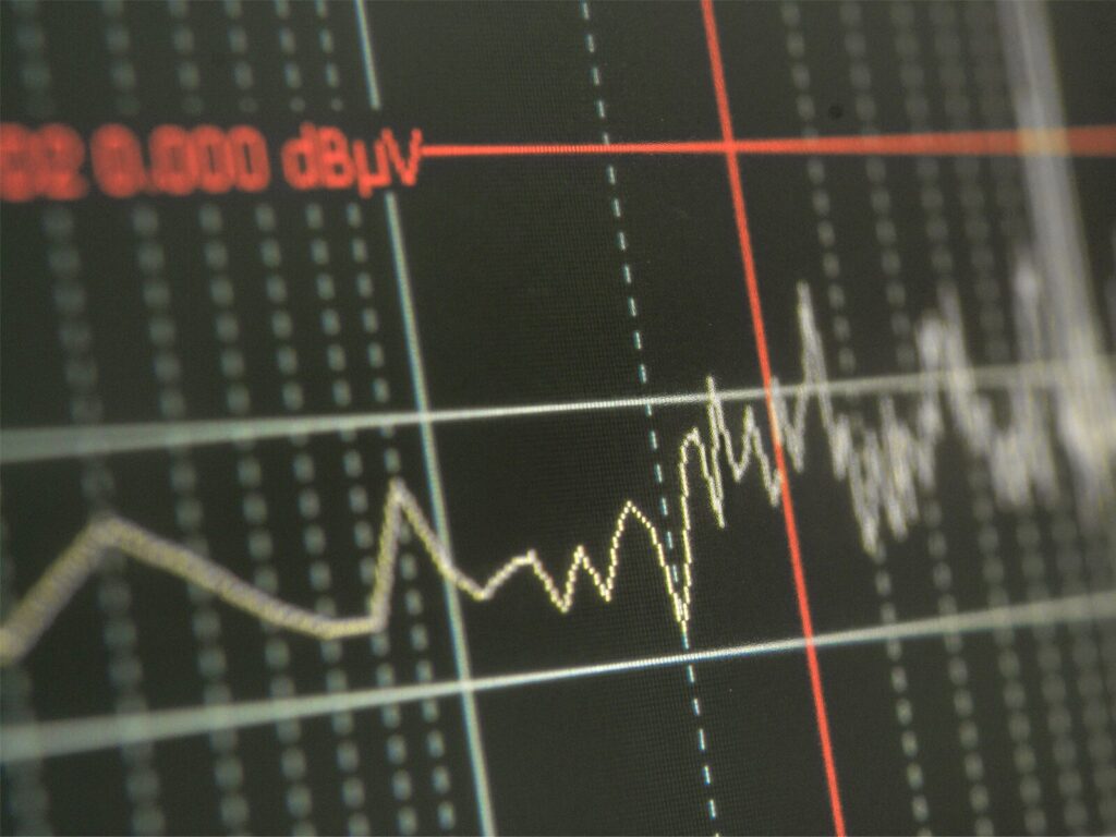 Focus on an electromagnetic interference testing receiver screen. It displays a device's electromagnetic emissions in terms of decibel microvolts.
