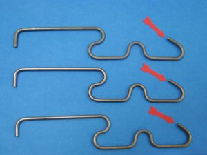 Three separated parts of a spring. Red arrows point to signs of fatigue on each part.