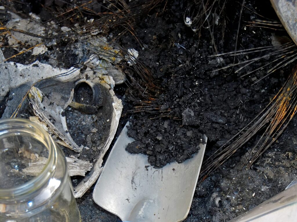 Forensic expert takes a sample of ash and debris by charred electrical wires
