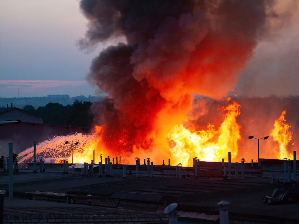 Massive fire at an industrial site. A giant plume of smoke rises.