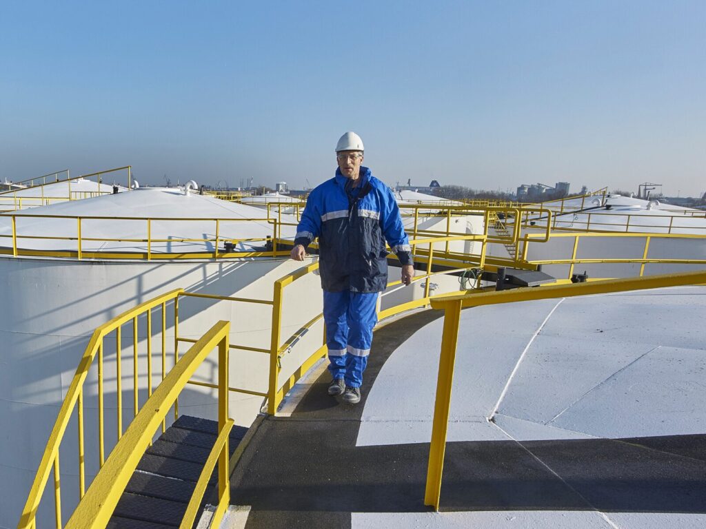 Man walks on a raised platform and staircase. He uses a guardrail to protect him from falling.