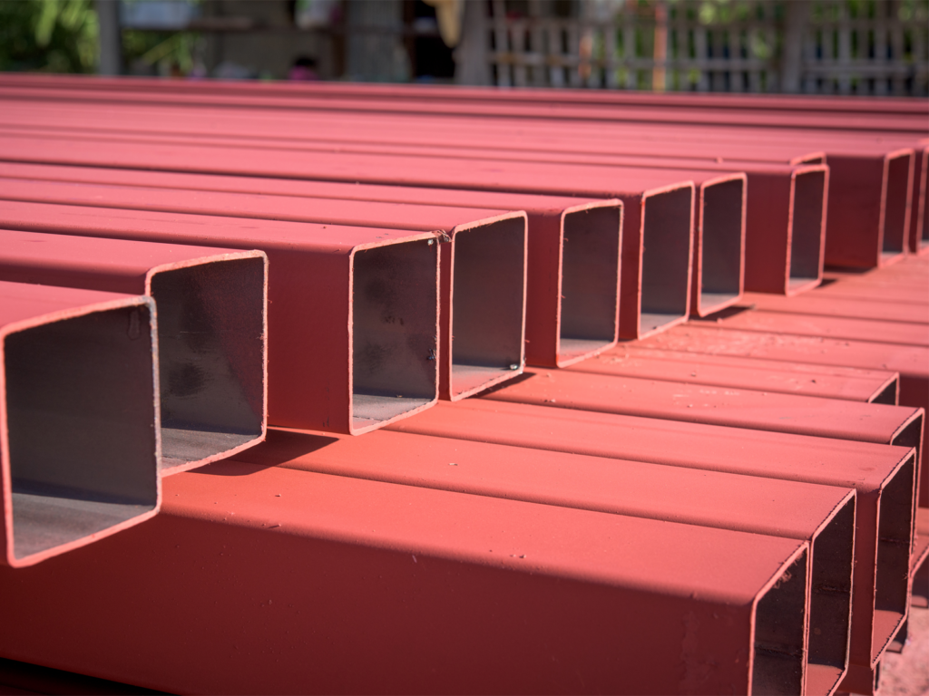 Stacks of red steel beams at a construction site