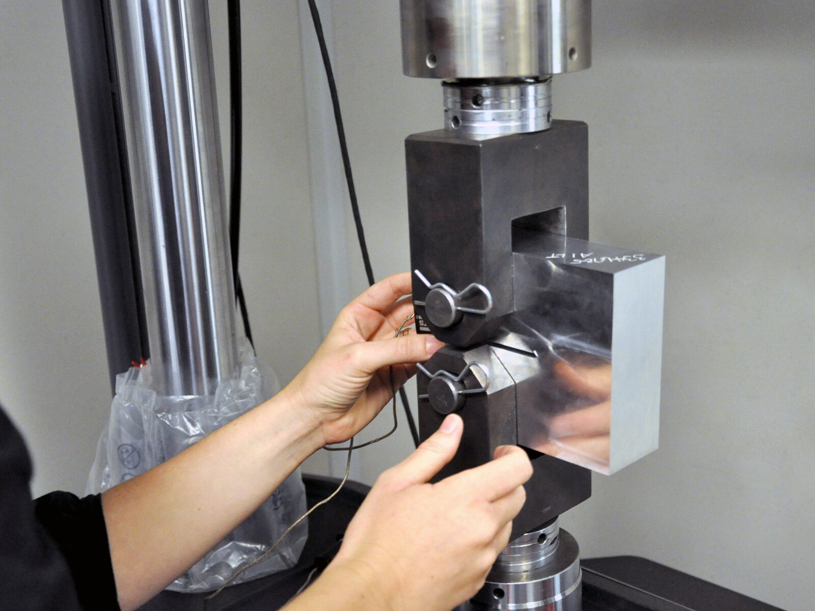 Technician loads metal block into a fatigue testing machine