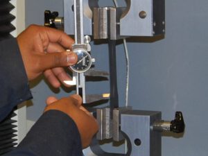 Technician loads a plastic specimen in a tensile testing machine